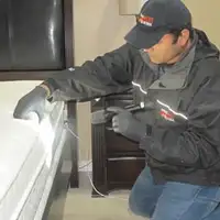 Bed bug inspection technician checking a mattress and bed frame for signs of infestation in Henderson, NV