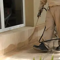 General pest control technician spraying exterior perimeter around a home in Henderson, NV