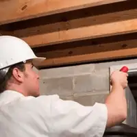 Termite inspection technician checking a basement wall and framing for termite activity in Henderson, NV